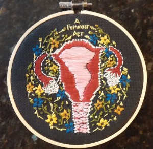 embroidered uterus with floral embellishments and the text "a feminist act"