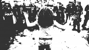 Stencil of a black woman stands in the foreground, back to the camera and hands up. She faces a line of police officers in riot gear