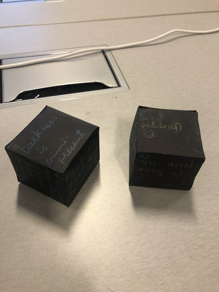 Two black cubes sit side-by-side, with the same poem in two languages. 