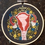 embroidered uterus with floral embellishments and the text "a feminist act"