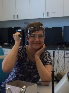 Woman wearing three pairs of safety glasses and holding a soldering iron incorrectly